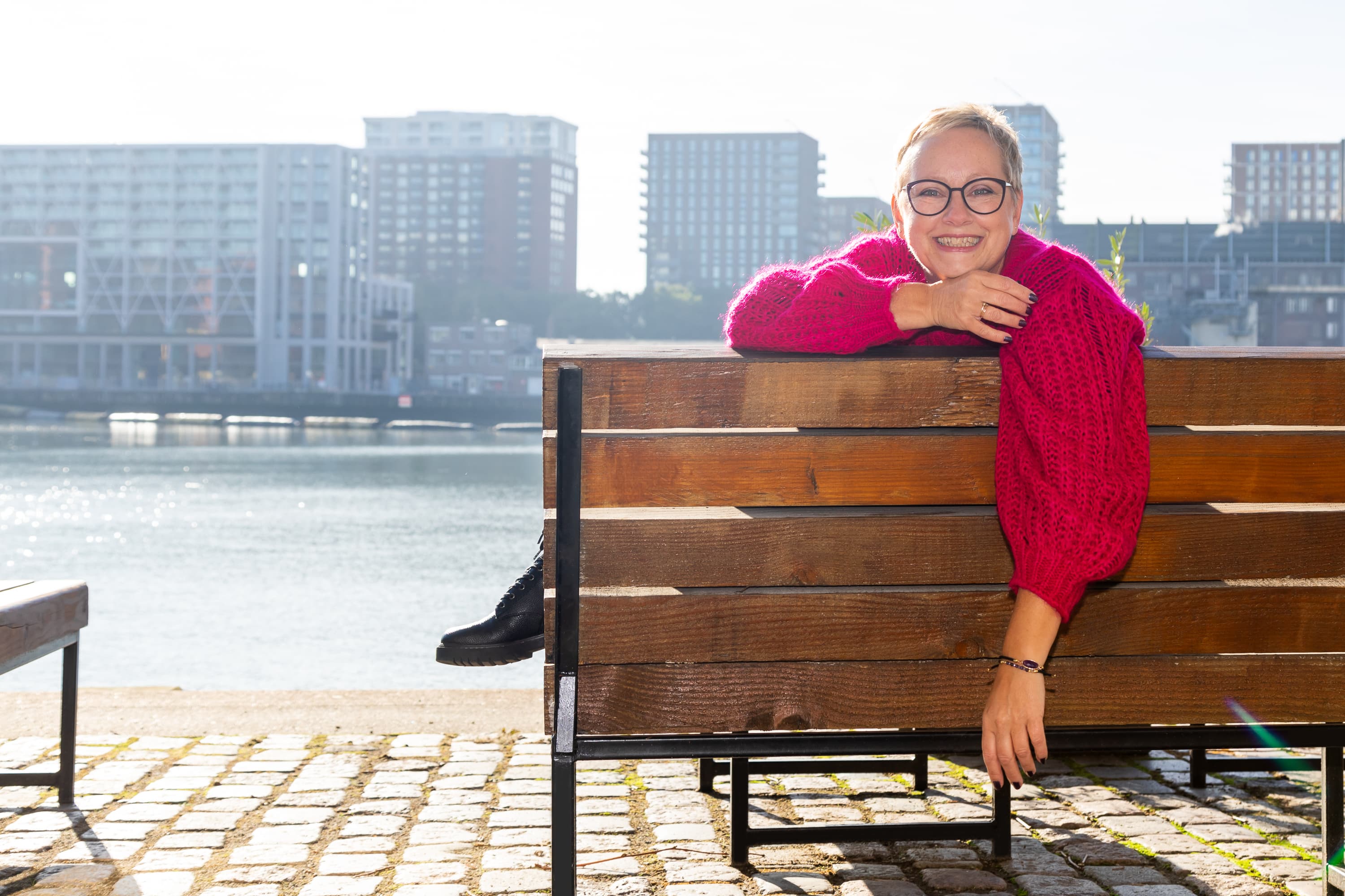 Joke van der Kraan, grafisch vormgever en eigenaar van VormBuilders, gefotografeerd in het stedelijke landschap van Rotterdam, waar haar professionele uitstraling en warme persoonlijkheid vastgelegd zijn tegen een achtergrond van dynamische architectuur.