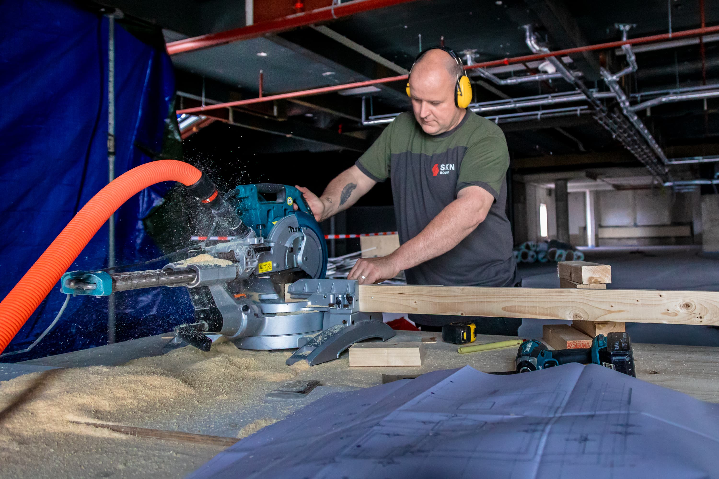 Fotoserie van Bart van den Bosch bij SKN Bouw in de Mall of the Netherlands. De beelden tonen bouwvakkers in bedrijfskleding van ViV Corporate Fashion, met aandacht voor details, vakmanschap en teamspirit.