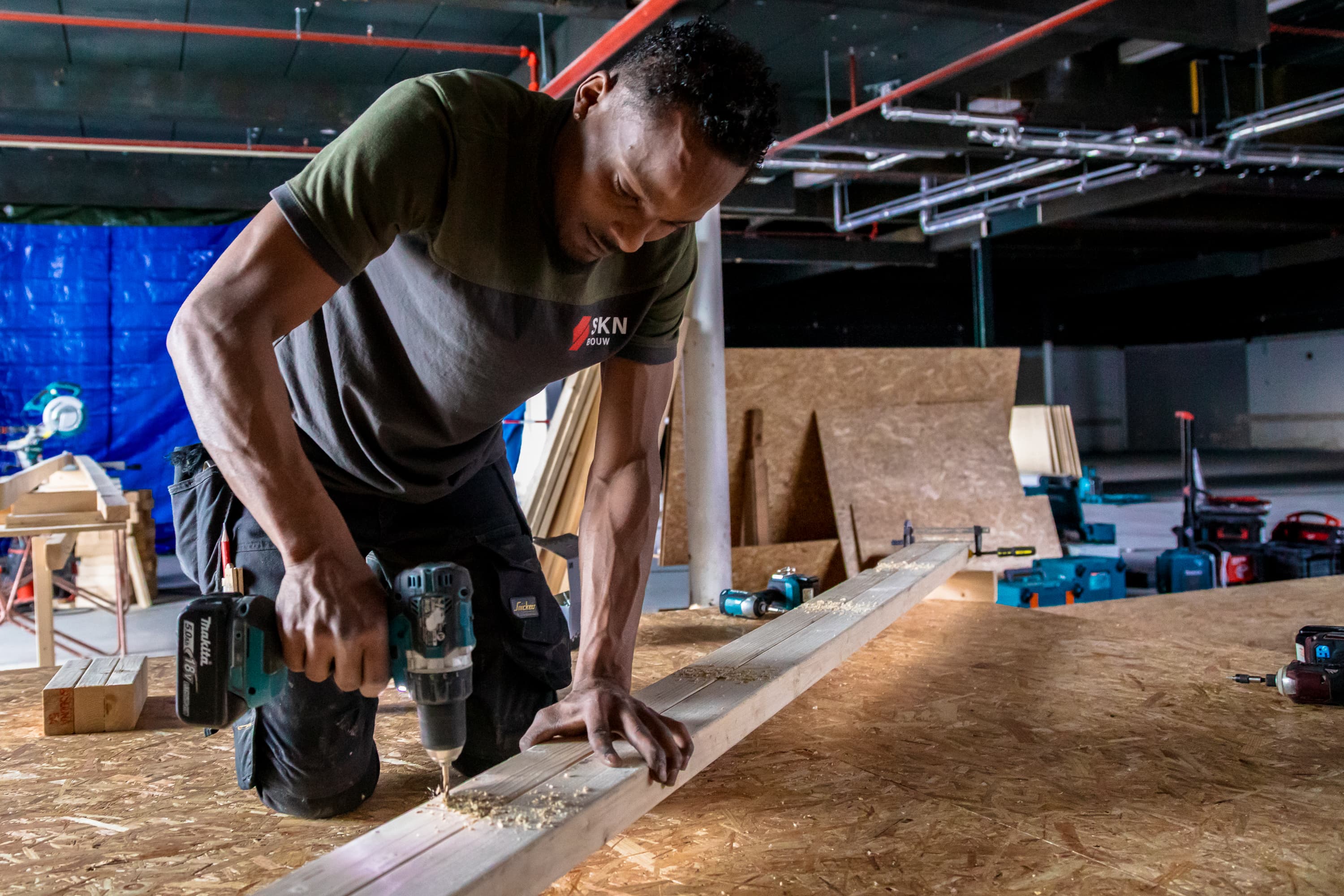 Fotoserie van Bart van den Bosch bij SKN Bouw in de Mall of the Netherlands. De beelden tonen bouwvakkers in bedrijfskleding van ViV Corporate Fashion, met aandacht voor details, vakmanschap en teamspirit.